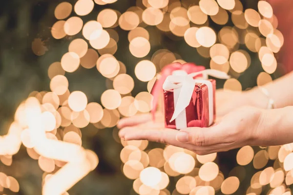 gift on hand with christmas bokeh light background - vintage effect filter