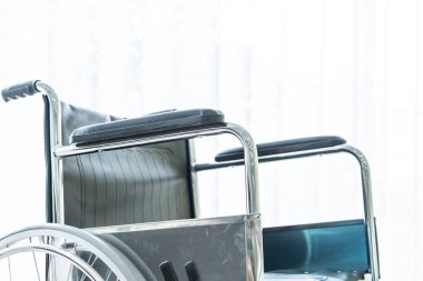 perde ve güneş ışığı ile bir odada boş tekerlekli sandalye