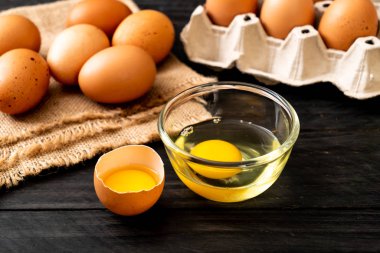 Ahşap masa üzerinde yumurta ile bir kırık kahverengi ve yumurta sarısı