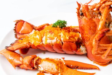 Soslu ıstakoz kuyruklu biftek ve beyaz arka planda karides yumurtaları.