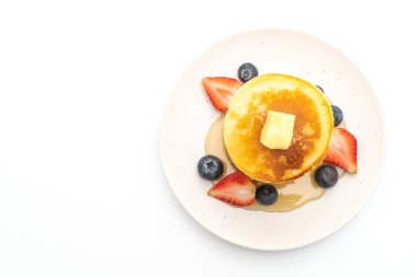 Tereyağlı krep, çilek, yabanmersini ve bal beyaz arka planda izole edilmiş.