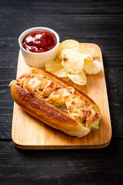 homemade lobster roll with potato chips on wooden board