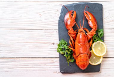 Sebzeli kırmızı ıstakoz ve siyah tabakta limon.