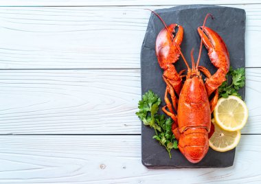 Sebzeli kırmızı ıstakoz ve siyah tabakta limon.