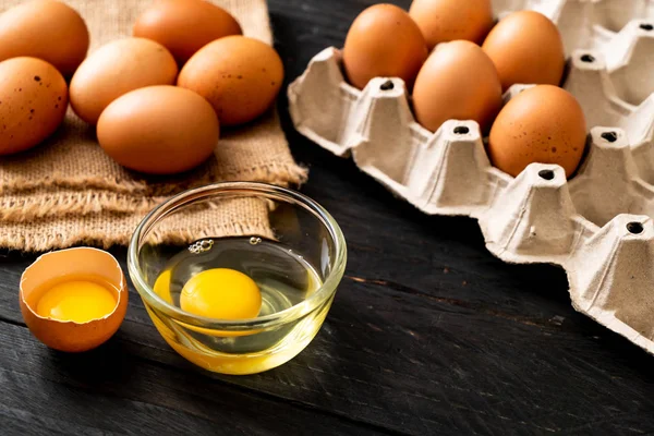 Ahşap masa üzerinde yumurta ile bir kırık kahverengi ve yumurta sarısı