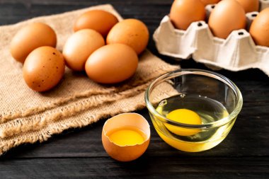 Ahşap masa üzerinde yumurta ile bir kırık kahverengi ve yumurta sarısı