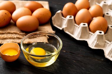 Ahşap masa üzerinde yumurta ile bir kırık kahverengi ve yumurta sarısı