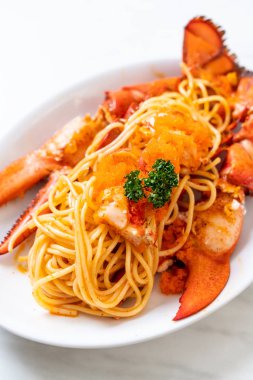 Beyaz tabakta karides yumurtalı ıstakoz spagettisi.