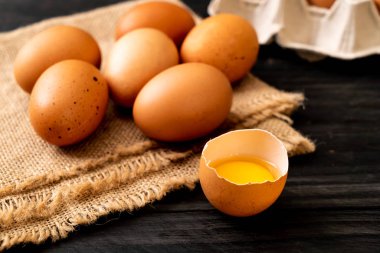 Ahşap masa üzerinde yumurta ile bir kırık kahverengi ve yumurta sarısı