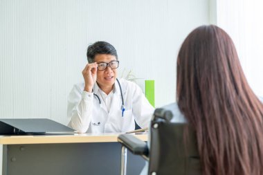 Asyalı doktor ve hasta Danışma ve masada otururken bir şey tartışırken vardır