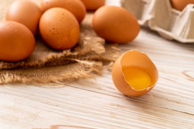 Ahşap masa üzerinde yumurta ile bir kırık kahverengi ve yumurta sarısı