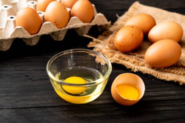 Ahşap masa üzerinde yumurta ile bir kırık kahverengi ve yumurta sarısı