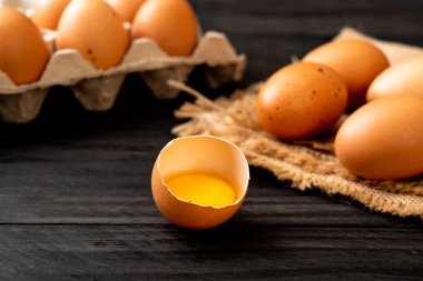 Ahşap masa üzerinde yumurta ile bir kırık kahverengi ve yumurta sarısı
