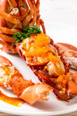 Soslu ıstakoz kuyruklu biftek ve beyaz arka planda karides yumurtaları.