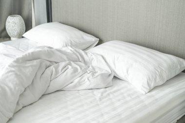 Beyaz yastık yatak ve yatak odasında kırışıklık dağınık battaniye ile