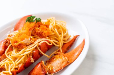 Beyaz tabakta karides yumurtalı ıstakoz spagettisi.