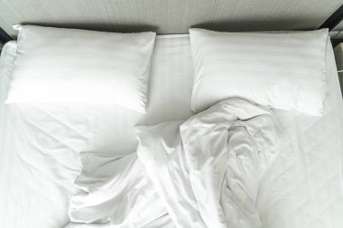 Beyaz yastık yatak ve yatak odasında kırışıklık dağınık battaniye ile