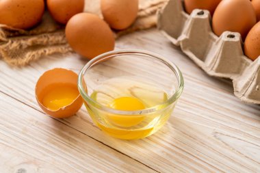 Ahşap masa üzerinde yumurta ile bir kırık kahverengi ve yumurta sarısı