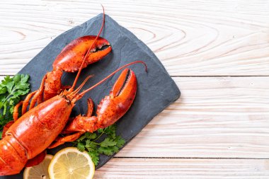 Sebzeli kırmızı ıstakoz ve siyah tabakta limon.