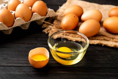 Ahşap masa üzerinde yumurta ile bir kırık kahverengi ve yumurta sarısı