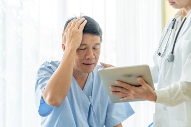 Asya kıdemli hasta hastane yatak kadın doktor - seçici odak noktası ile tartışırken.