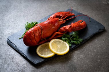 Sebzeli kırmızı ıstakoz ve siyah tabakta limon.