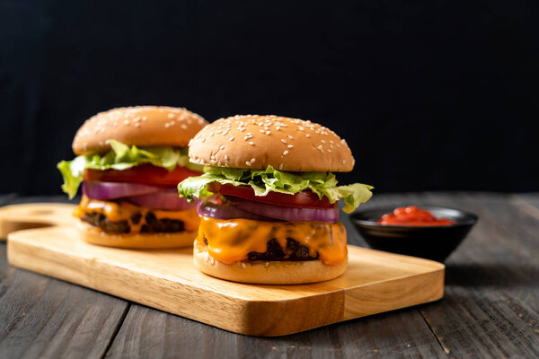 свежий вкусный говяжий бургер с сыром и кетчупом на деревянном фоне
