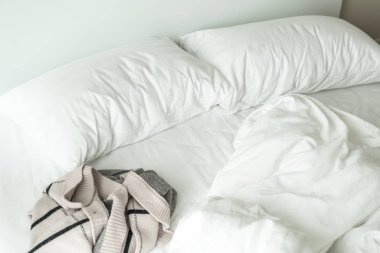 Beyaz yastık yatak ve yatak odasında kırışıklık dağınık battaniye ile