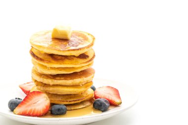 Tereyağlı krep, çilek, yabanmersini ve bal beyaz arka planda izole edilmiş.