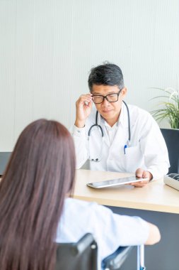 Asyalı doktor ve hasta Danışma ve masada otururken bir şey tartışırken vardır