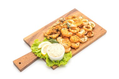 Beyaz arka plan üzerinde izole soslu kızarmış deniz ürünleri (mürekkep, karides, midye)