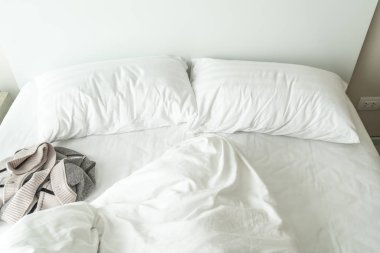 Beyaz yastık yatak ve yatak odasında kırışıklık dağınık battaniye ile