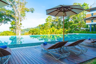 Otelde ve tatil beldesinde yüzme havuzunda güzel şemsiye ve sandalye - tatil kavramı
