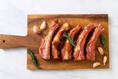 Tahtadaki malzemelerle birlikte kızartılmaya hazır taze çiğ domuz pirzolası.