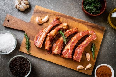 Tahtadaki malzemelerle birlikte kızartılmaya hazır taze çiğ domuz pirzolası.