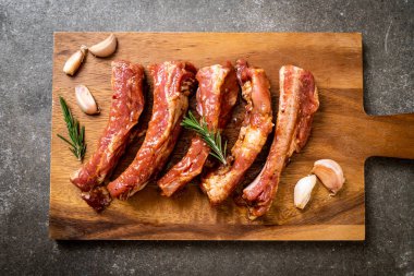 Tahtadaki malzemelerle birlikte kızartılmaya hazır taze çiğ domuz pirzolası.