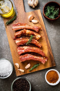 Tahtadaki malzemelerle birlikte kızartılmaya hazır taze çiğ domuz pirzolası.