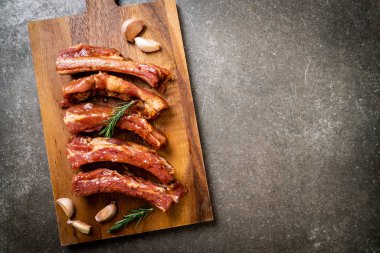 Tahtadaki malzemelerle birlikte kızartılmaya hazır taze çiğ domuz pirzolası.