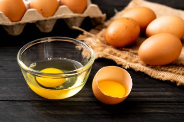 Ahşap masa üzerinde yumurta ile bir kırık kahverengi ve yumurta sarısı