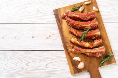 Tahtadaki malzemelerle birlikte kızartılmaya hazır taze çiğ domuz pirzolası.