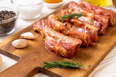 Tahtadaki malzemelerle birlikte kızartılmaya hazır taze çiğ domuz pirzolası.