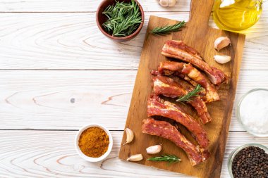 Tahtadaki malzemelerle birlikte kızartılmaya hazır taze çiğ domuz pirzolası.