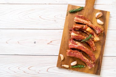 Tahtadaki malzemelerle birlikte kızartılmaya hazır taze çiğ domuz pirzolası.