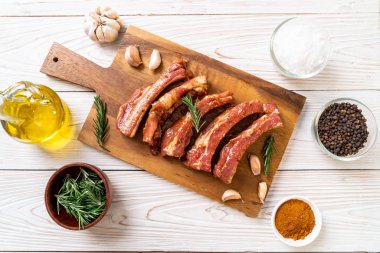 Tahtadaki malzemelerle birlikte kızartılmaya hazır taze çiğ domuz pirzolası.