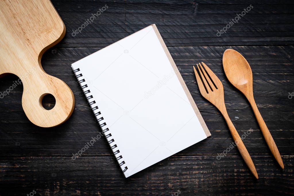 blank notebook for text note on wooden surface and wooden spoon and fork with copy sapce