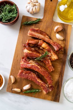 Tahtadaki malzemelerle birlikte kızartılmaya hazır taze çiğ domuz pirzolası.