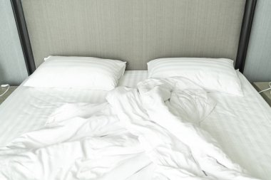 Beyaz yastık yatak ve yatak odasında kırışıklık dağınık battaniye ile