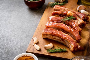 Tahtadaki malzemelerle birlikte kızartılmaya hazır taze çiğ domuz pirzolası.