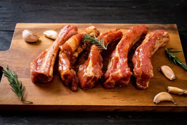 Tahtadaki malzemelerle birlikte kızartılmaya hazır taze çiğ domuz pirzolası.