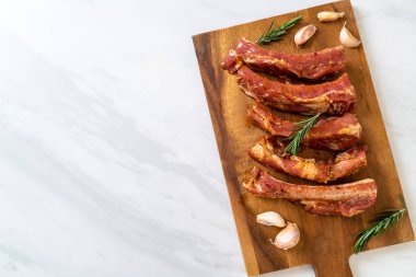 Tahtadaki malzemelerle birlikte kızartılmaya hazır taze çiğ domuz pirzolası.